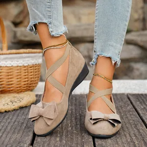 Dettaglio delle scarpe con zeppa in pelle scamosciata da donna con fiocco e cinturini.