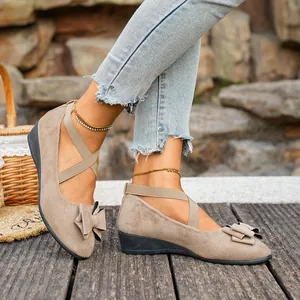 Dettaglio di scarpe beige scamosciate con zeppa, fiocco e cinturini elastici incrociati