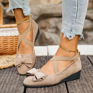 Dettaglio di décolleté con zeppa in camoscio beige con fiocco e cinturini.