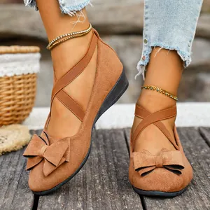Primo piano di scarpe basse in camoscio marrone con fiocco e cinturini incrociati
