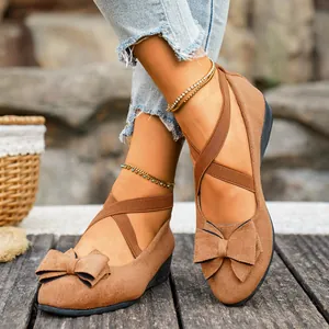 Primo piano di scarpe con zeppa in camoscio marrone con fiocco decorativo e cinturini elastici