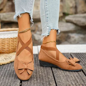 Dettaglio scarpe con zeppa in camoscio marrone con fiocco e cinturini incrociati