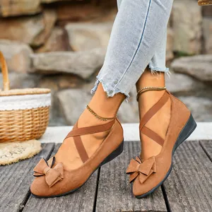 Dettaglio di eleganti scarpe con zeppa in pelle scamosciata marrone con fiocco.