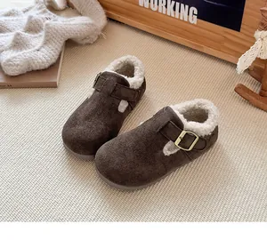 Primer plano de zapatos de ante marrón para niños con forro polar y hebilla dorada.