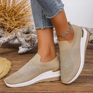 Nahaufnahme von stilvollen beigen Flyknit-Keilsneakern mit Strasssteinen an den Füßen.