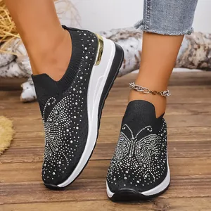 Nahaufnahme schwarzer Strick-Keilsneaker mit Strass-Schmetterling am Modell