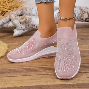 Detailaufnahme von pinkfarbenen Fly-Knit-Wedge-Sneakern mit funkelndem Strassbesatz.