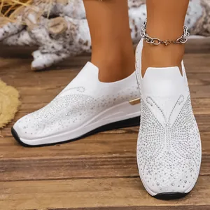 Detailaufnahme der weißen Keilsneaker mit funkelnden Strasssteinen und Flyknit-Gewebe.