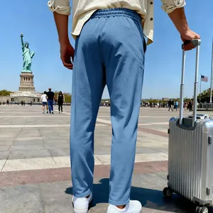 Back view of men's loose blue knit casual pants in a travel setting with suitcase