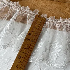 Detail of white butterfly embroidered mesh lace trim with a ruler for size measurement