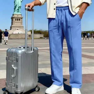 Men's light blue knitted straight-leg casual pants styled with a silver suitcase