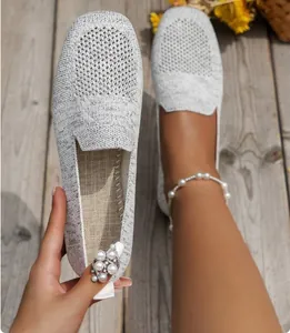 Close-up of breathable grey knitted flat loafers for women in a summer setting.