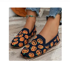 Close-up of navy blue knit flat shoes featuring festive orange pumpkin print patterns