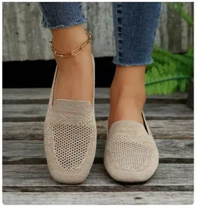 Macro detail of women's breathable knit loafers worn on feet in a natural outdoor setting.