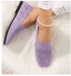Close-up of lavender knit flat loafers on white faux fur background with pearl anklet