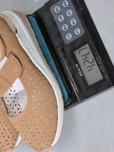 Detailed weight measurement showing a brown laser-cut breathable wedge shoe on a scale