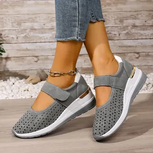 Close-up detail of grey breathable hollow-out wedge shoes with adjustable velcro straps.