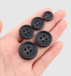 Macro detail of high-quality black resin 4-hole buttons for coats and jackets on hand