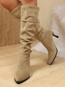 Vista detallada de botas stiletto de gamuza beige con punta fina y correas de hebilla