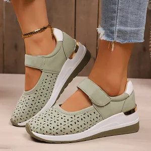 Detail shot of green hollowed-out wedge sneakers with velcro strap and gold heel accents.