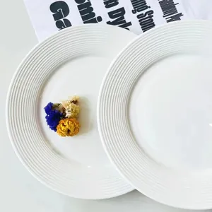 Dettaglio dell'elegante trama a coste concentriche su un piatto in ceramica bianca.