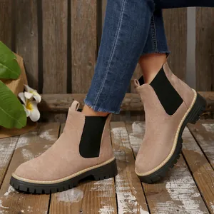 Stylish women's beige suede Chelsea boots featuring a thick black platform sole on a model