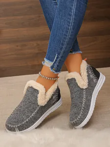 Détail de bottes de neige grises avec doublure en fausse fourrure crème douillette.