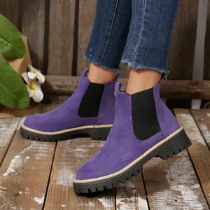 Close-up view of women's purple suede chunky platform Chelsea boots on a rustic wooden floor
