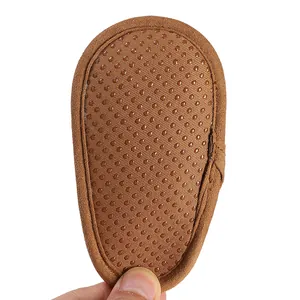 Close-up macro view showing the non-slip dot sole pattern on brown suede baby winter boots