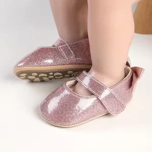 Detailed close-up of pink glittery baby walking shoes with bow detail and soft sole