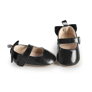 Detail of black glitter baby pre-walker shoes with cute bow and velcro strap.