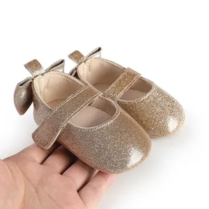 Close-up detail of sparkly gold baby girl walker shoes featuring a bow and strap