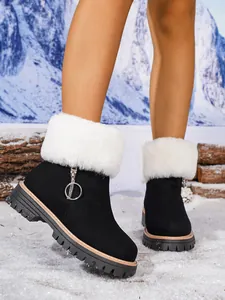 Close-up of black platform snow boots with white faux fur trim and side zipper detail