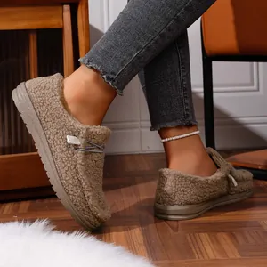 Detailed view of women's khaki warm fuzzy loafers worn on feet in a cozy home setting