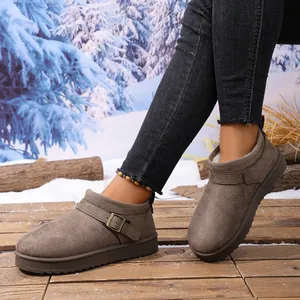 Detail view of brown suede snow boots with plush lining and buckle on a snowy background.