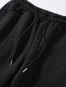 Dettaglio macro della texture nera goffrata sui pantaloni sportivi da uomo con coulisse