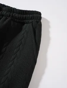 Dettaglio ravvicinato di pantaloni sportivi neri da uomo con trama in maglia a trecce fine
