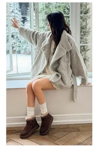 Lifestyle shot of brown platform snow boots with ethnic embroidery worn with cozy winter coat