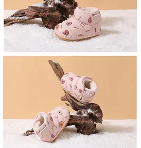 Close-up of pink baby snow boots with fleece lining and cute bear prints in snow scene
