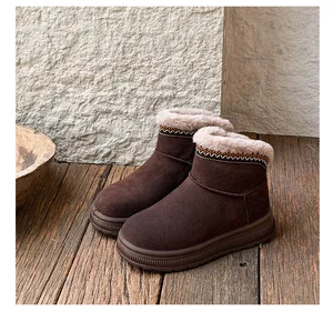 Detailed view of dark brown snow boots with ethnic embroidery and plush lining on wood floor