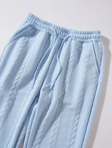 Dettaglio dei pantaloni sportivi azzurri in maglia a trecce con coulisse.