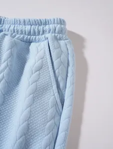 Dettaglio dei pantaloni sportivi azzurri da uomo con particolare trama a treccia