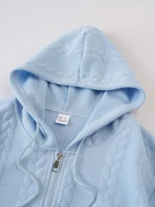 Close-up view of a light blue textured hoodie showing the collar, size tag, and zipper.