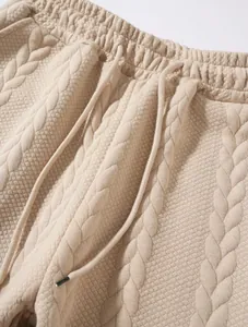 Dettaglio ravvicinato di joggers beige trecciati da uomo con vita regolabile tramite cordino