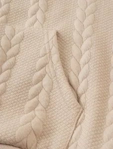 Detailed close-up of beige cable knit and diamond textured fabric on casual men's hoodie