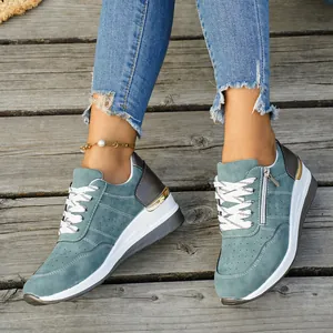Close-up of teal women's platform sneakers with white laces and side zipper on wood