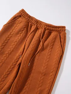 Dettaglio di pantaloni in maglia trecciata arancione con coulisse elastica in vita