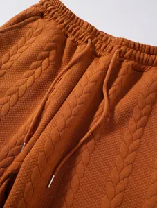 Dettaglio di pantaloni maschili in maglia testurizzata ruggine con cordoncino