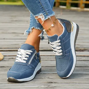 Close-up of blue women's platform sneakers with white laces and side zipper detail.