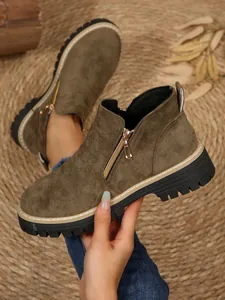 Détail des bottines Martin en daim vert olive avec fermeture éclair et semelle.